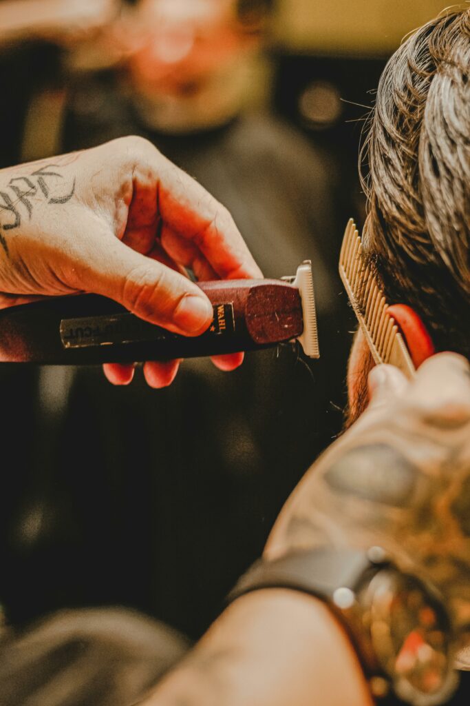 Barbier tatoué réalisant les finitions d'une coupe à la tondeuse — Bien Raser Cannes